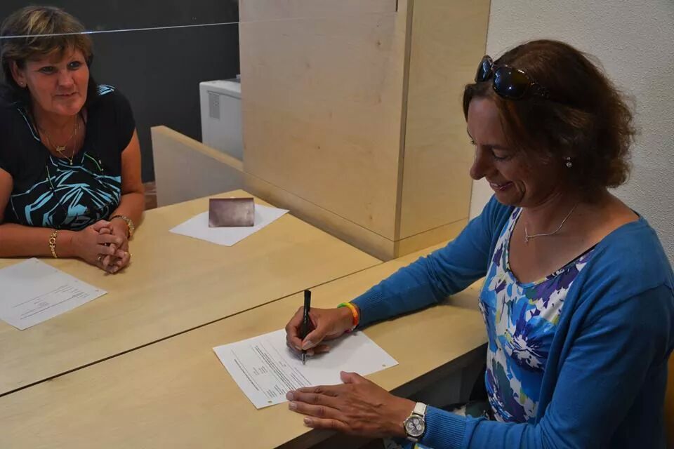 een transvrouw die aan een balie een formulier invult om haar registratie te wijzigen.